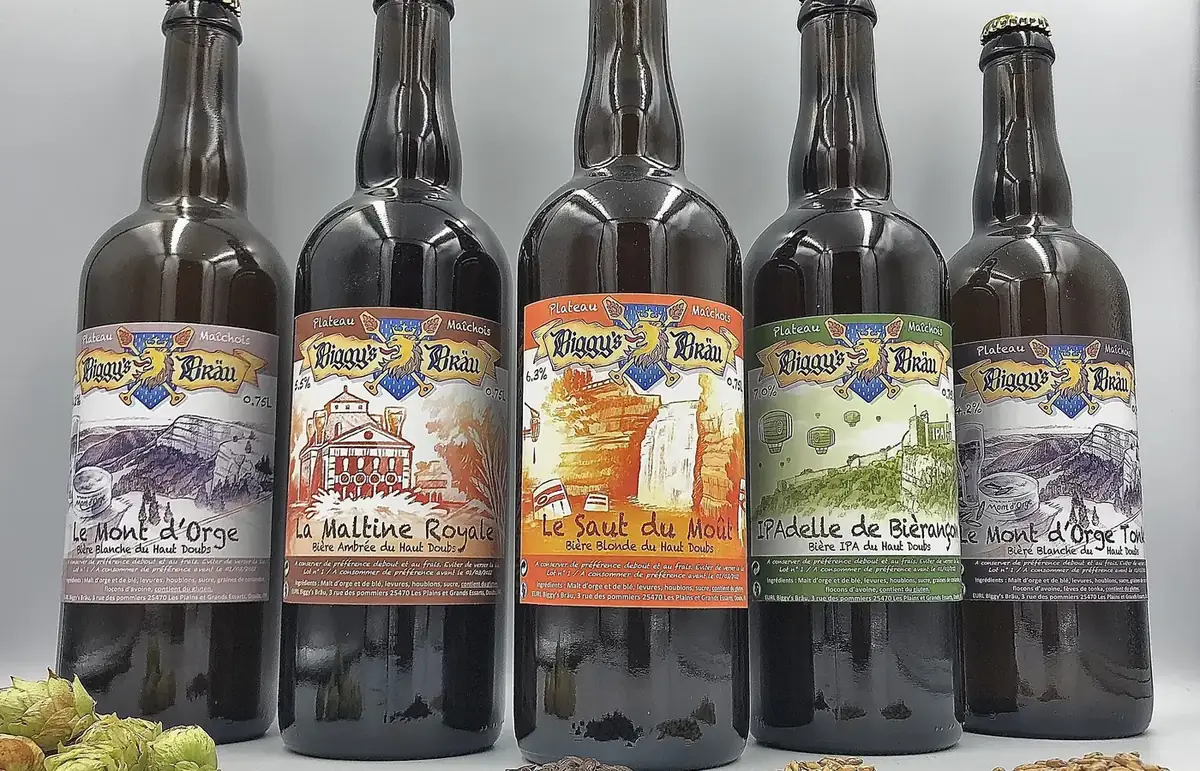 Cinq bouteilles Biggy's Bräu alignées, avec du houblon et du malt