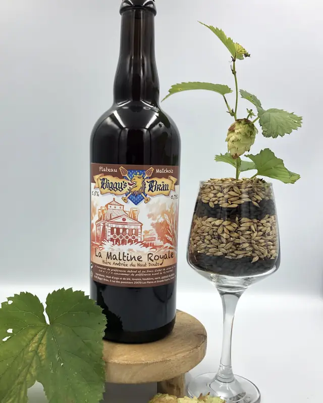 Bouteille de Maltine Royale à côté d'un verre de malt et de houblon