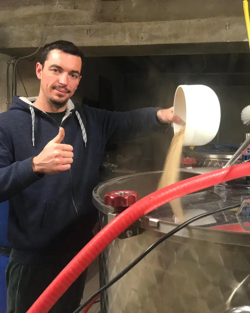Titouan versant les grains dans la cuve de brassage